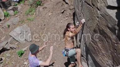运动员攀岩者爬在悬崖上，伸手抓住。